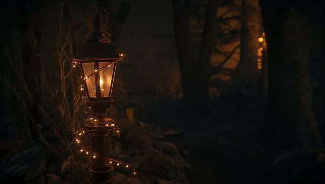 Vintage Lamp Post with Candle and Fairy Lights Casting Amber Glow on Garden Path at Night