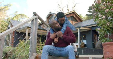 African american father and son sharing playful moment on steps at family home