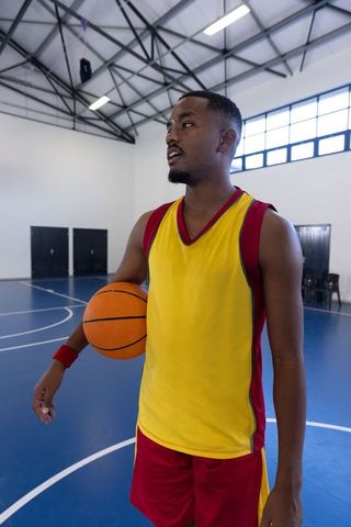 African American Male Athlete Holding Basketball on Gym Court