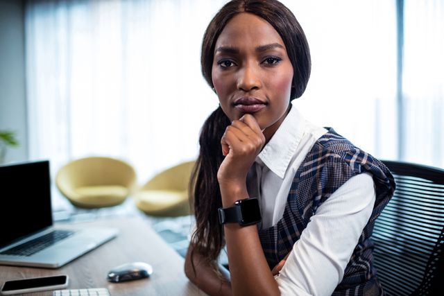 A confident businesswoman sitting at her desk in a modern office, looking directly at the camera. This can be used for articles on career development, professional growth, women's empowerment, corporate settings, and workplace diversity.