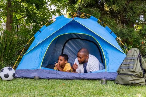 African american father and son camping in backyard tent bonding over soccer and nature