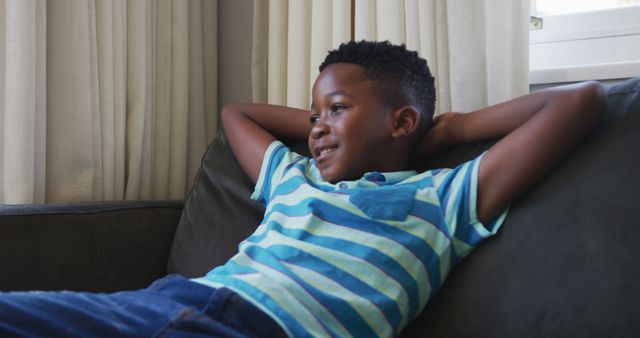 Relaxed Child Lounging on Couch at Home in Sunlight - Download Free Stock Images Pikwizard.com