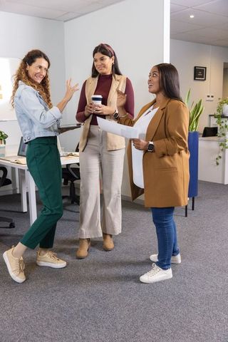 Multicultural female team sharing ideas and documents in modern open-plan office