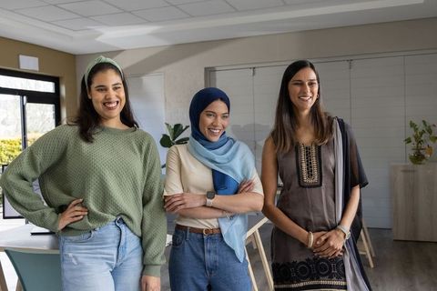 Diverse women smiling and standing together in bright coworking space with plants