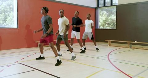 Four african american men training agility drill in indoor gymnasium