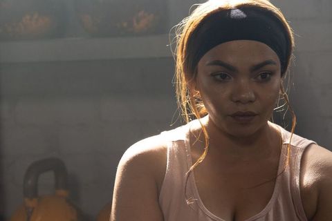 Determined asian woman lifting kettlebell, sweating in tank top and headband