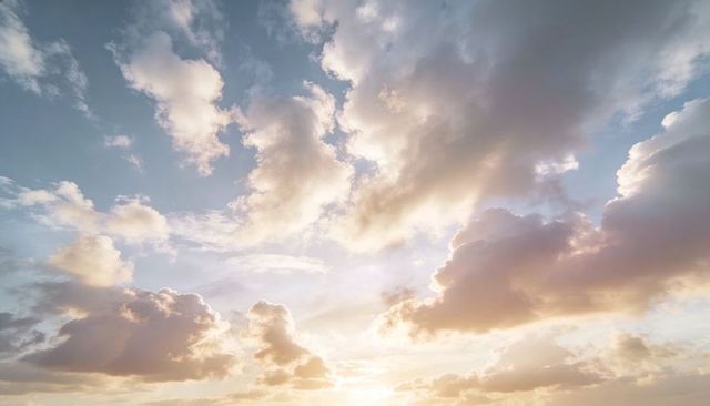Cumulus Clouds Glowing Over Open Sky at Sunrise with Warm Sun Rays Breaking Through