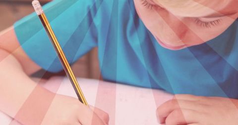 Focused child writing homework with pencil closeup sunburst light studying at desk