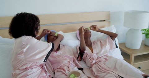 Mother and daughters enjoying at-home spa night wearing pink satin robes