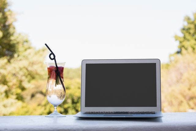Laptop and cocktail drink on retaining wall at restaurant - Download Free Stock Photos Pikwizard.com