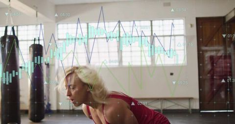 Female Athlete Doing Forward Bend in Boxing Gym with Digital Performance Charts Overlay