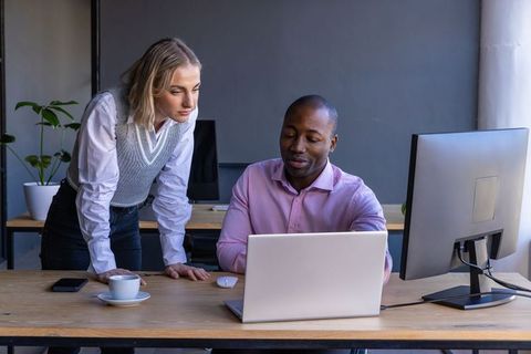 Diverse coworkers analyzing business data on laptops and monitors