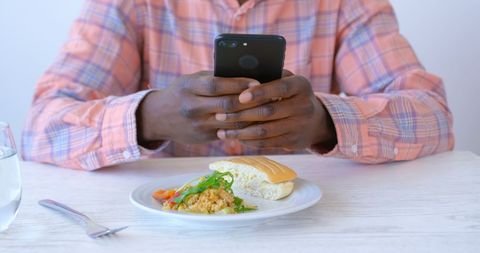 Casual Businessperson Checking Smartphone Balancing Work During Breakfast