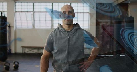 Fit trainer posing with hand on hip in gym displaying augmented reality workout overlays