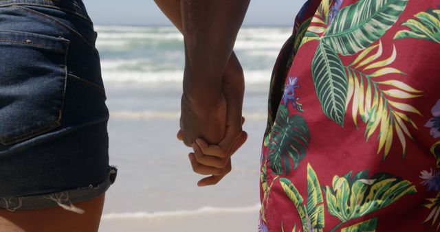 Diverse couple holding hands close up on sunny beach. Togetherness, summer, vacations and free time, unaltered.