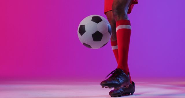 Vibrant image of a soccer player kicking a football in a studio with a colorful background. Perfect for sports-themed advertisements, athletic wear promotions, or soccer event posters. Great for illustrating concepts related to sportsmanship, agility, and team spirit.
