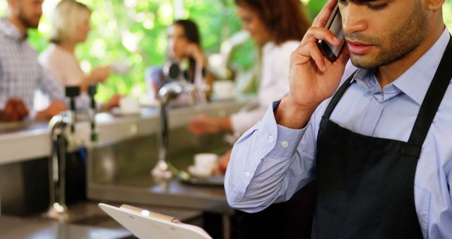 Busy cafe worker taking phone call behind counter - Download Free Stock Images Pikwizard.com