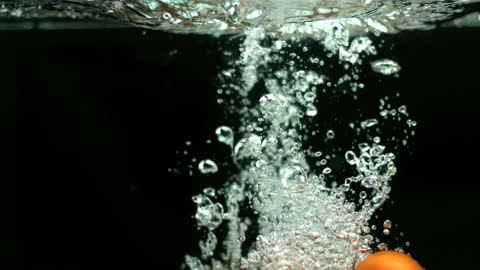 Fresh Tomatoes Dropping in Water with Bubbles and Splash