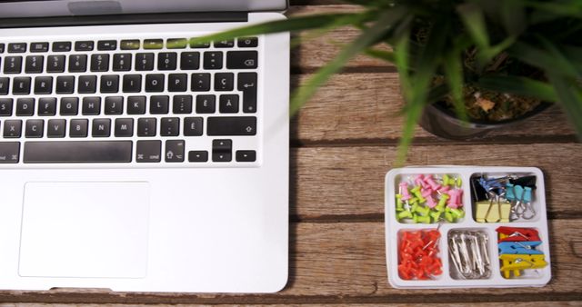 Close-up angle of desk shows laptop with organized office supplies in tray. Indicates a neat work environment. Useful for themes of work-from-home, studying, office management. Representation of keeping workspace tidy and boost in productivity.