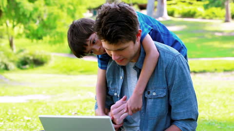 Father and Son Enjoying Laptop Time in Park