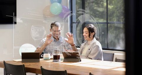 Team collaborating with augmented reality tablets at bright wooden meeting table