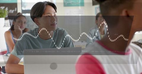 Teen asian student focusing on laptop with waveform hud overlay for digital learning