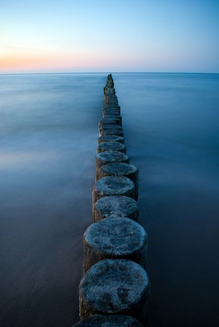 Serene Blue Hour Ocean Scene with Aligned Wooden Posts - Download Free Stock Photos Pikwizard.com