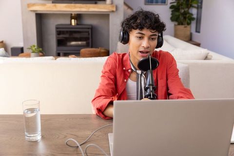 Young male podcaster recording podcast in modern living room