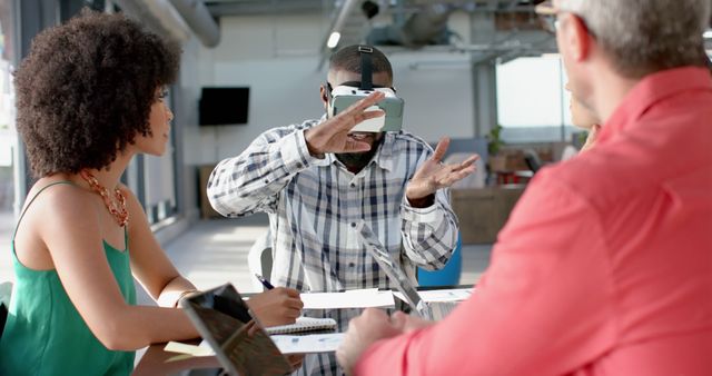 Group of young professionals in a contemporary office environment using a virtual reality headset. Ideal for themes on team collaboration, tech innovation, and modern workplaces. Useful for articles or marketing materials on digital transformation, tech meetings, and the future of work.