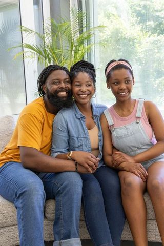 Smiling african american family relaxing on light sofa in bright modern living room