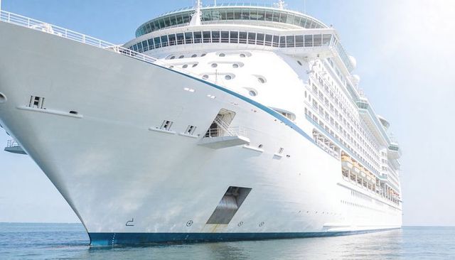 Luxury white cruise ship bow gliding across calm blue sea under bright sunlight
