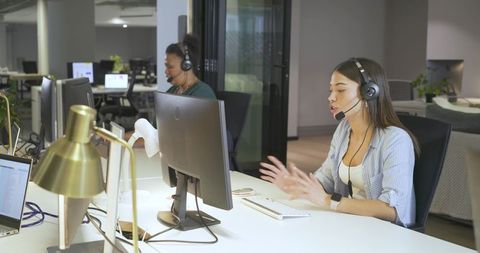 Indian woman speaking and gesturing while providing customer support in modern open-plan office
