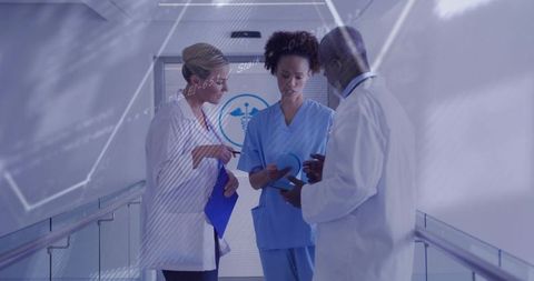 Medical team reviewing tablet and patient files in hospital corridor