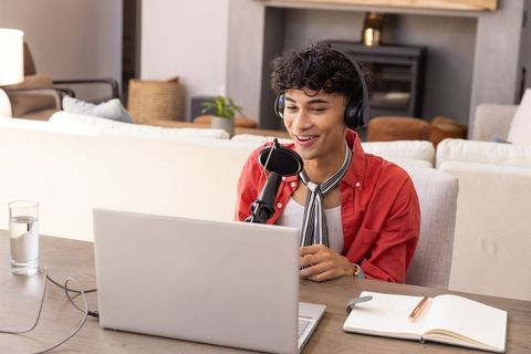 Man Podcasting from Modern Living Room with Laptop and Microphone