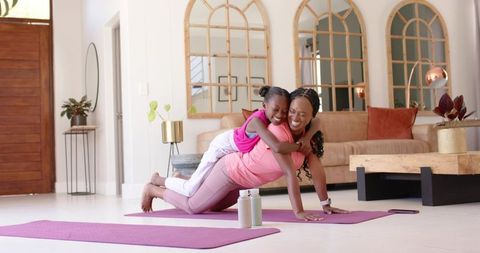 African american mother and daughter exercising at home sharing playful plank, family fitness