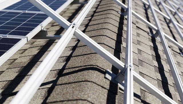 Solar panel mounting rails on asphalt shingle roof casting geometric shadows for pv systems