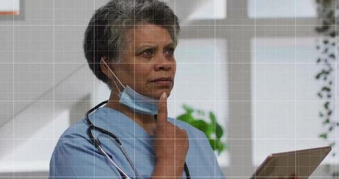 Senior Nurse Contemplating in Clinic With Tablet