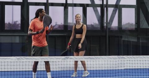 Diverse players capturing excitement in indoor padel tennis match