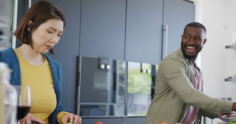Smiling multicultural couple preparing food in modern kitchen