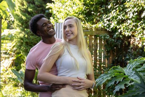 Caring couple embracing in leafy garden with sunlit smiles
