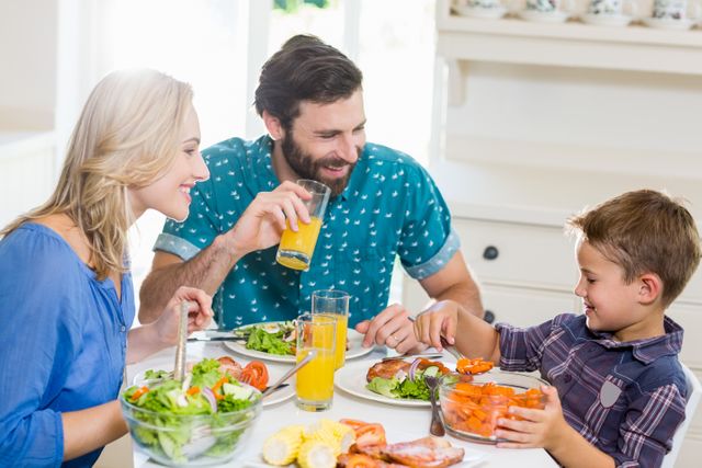 Happy family talking to each other while having meal in kitchen at home