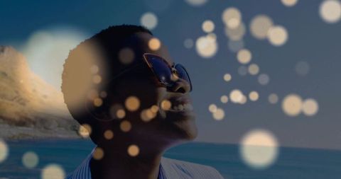 Smiling Woman with Sunglasses at Scenic Beach with Bokeh Effect