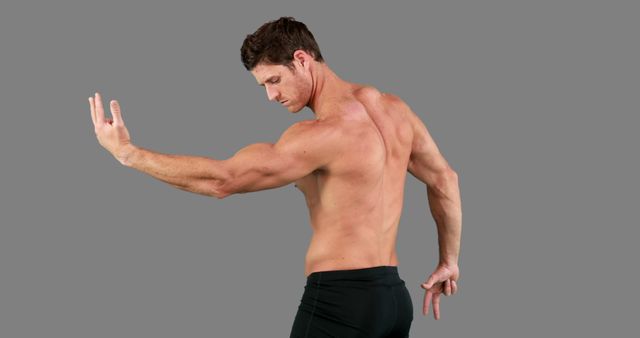 A muscular Caucasian man is posing to show off his well-defined physique, with copy space. His stance suggests a focus on fitness or bodybuilding, emphasizing strength and physical conditioning.