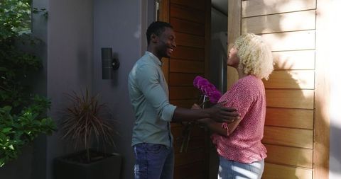 Man Surprising Woman with Flowers at Home Entrancedoor