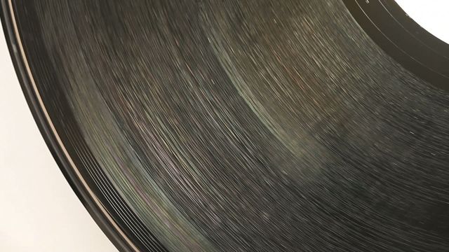 Close-up of a vintage vinyl record rotating against a white background. Ideal for themes related to music, retro culture, audio technology, and vintage aesthetics. Could be used in advertising for music equipment, retro-themed blogs, or as a dramatic visual element in multimedia projects.