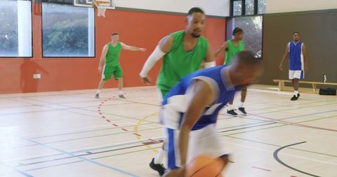 African american center forcing turnover while guard drives and shooting on indoor basketball court