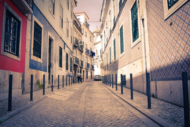 Narrow cobblestone alley with colorful buildings in Lisbon, Portugal, showcasing European urban charm. Colorful facades of old town architecture add character to this scenic cityscape. Ideal for promoting tourism, travel blogs, or architectural features of historic districts.