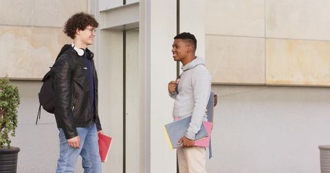 College students standing and talking on campus with backpacks and notebooks