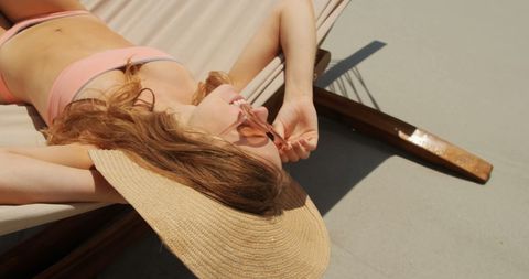 Caucasian Woman Relaxing on Beach Hammock with Sun Hat
