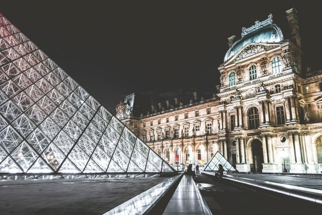 The photograph captures the iconic Louvre Museum in Paris, illuminated beautifully against the night sky, accompanied by the modern glass pyramid. This stunning contrast of historical and contemporary architecture can be used in travel guides, tourism websites, educational materials, and promotional content for Parisian landmarks.